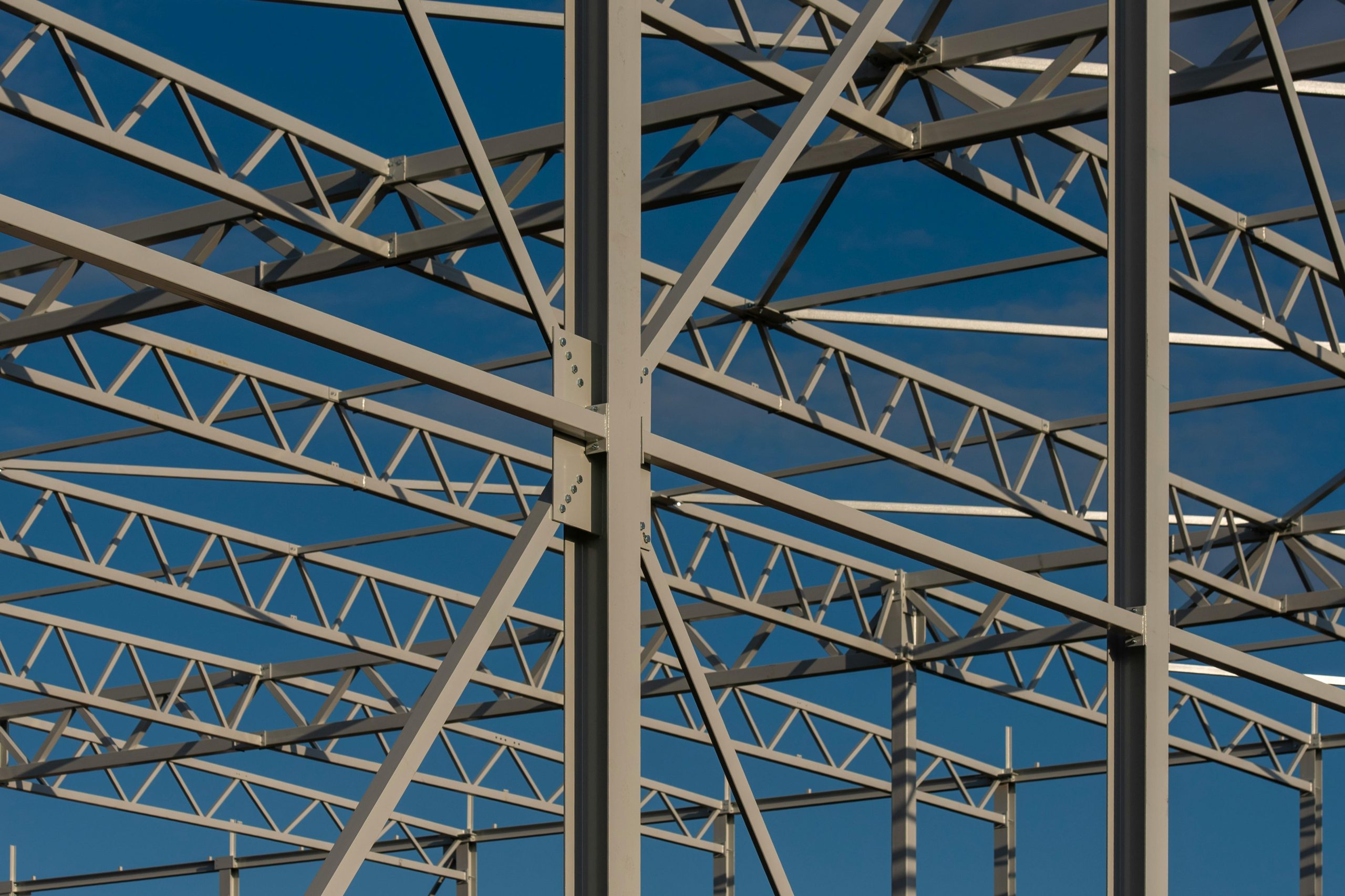 Detailed view of a steel framework structure against a blue sky, showcasing modern construction elements.